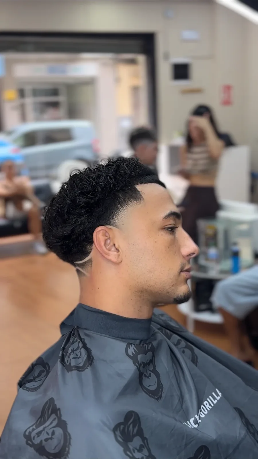 Burst fade con rizos definidos y línea en la sien, por Juseph